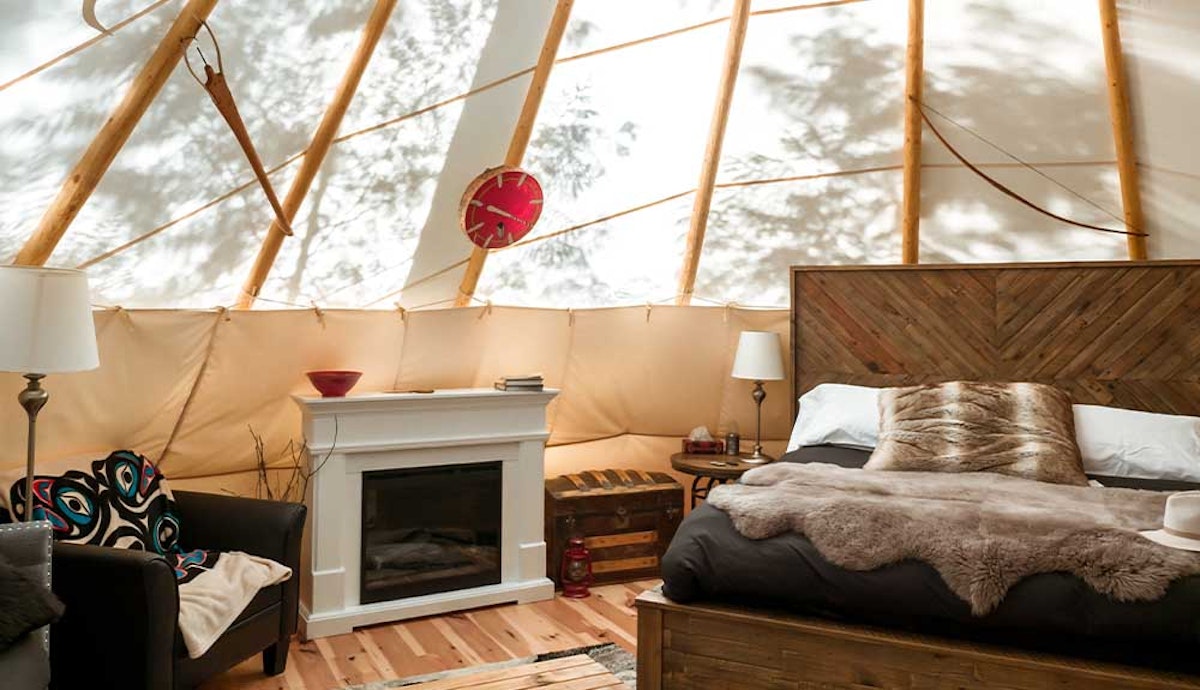 A bedroom in a tepee with a bed and a fireplace.