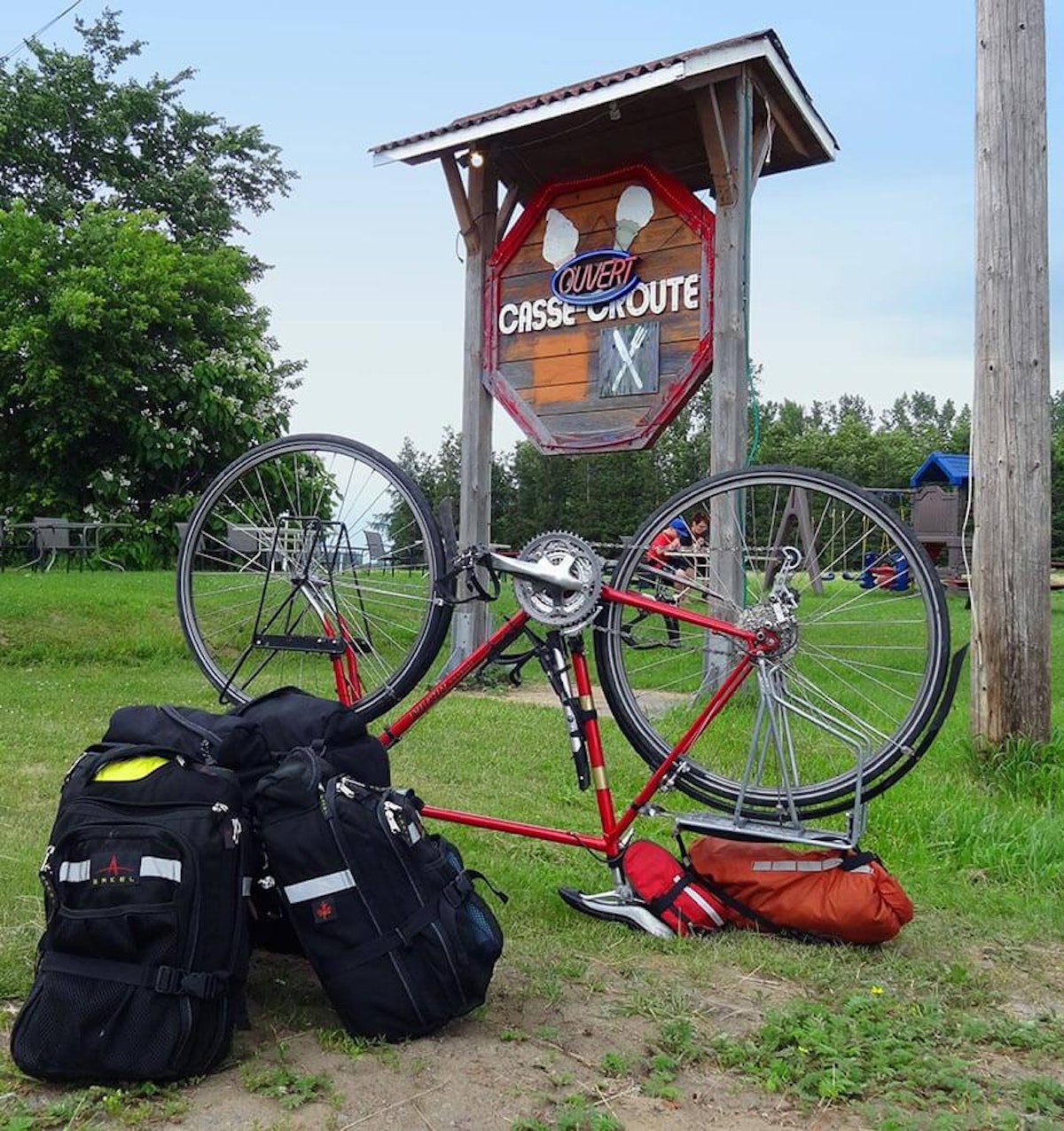 A bike with a backpack on the ground next to a sign.