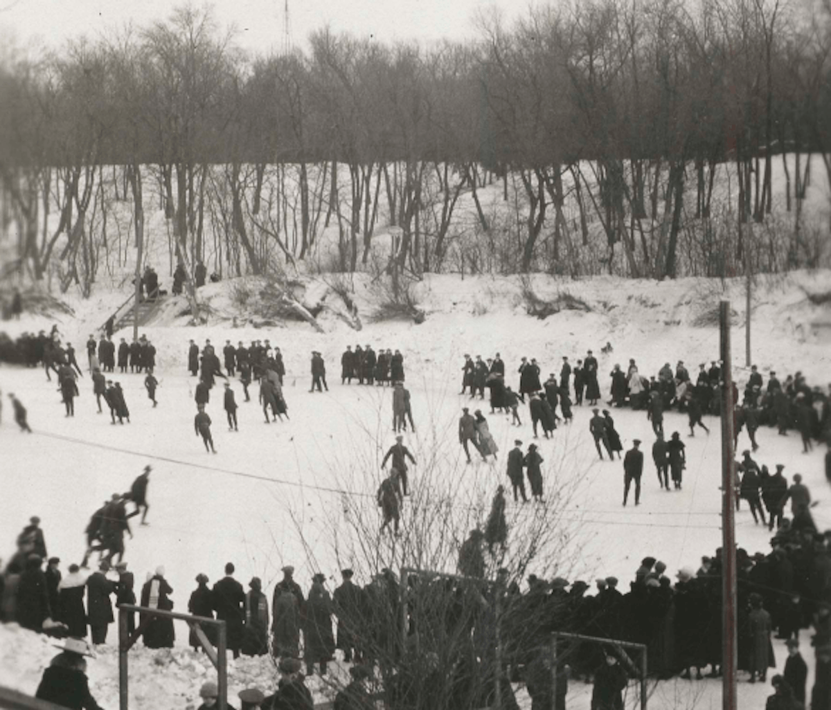 Groups of people gathered on a snowy landscape, many standing on a frozen body of water.