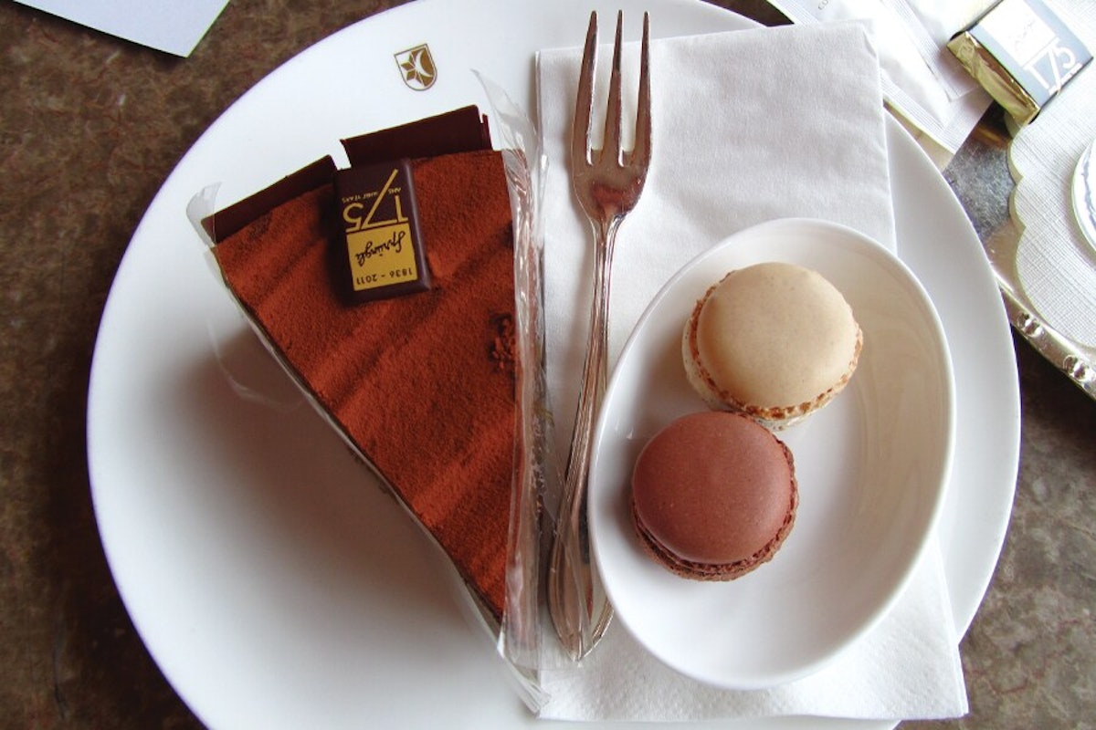 A piece of chocolate cake and macaroons on a plate.