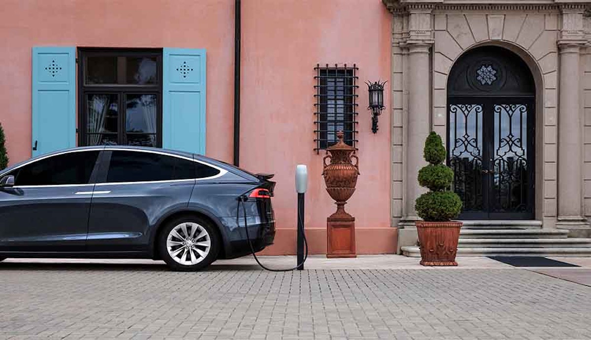 A tesla model x parked in front of a house.