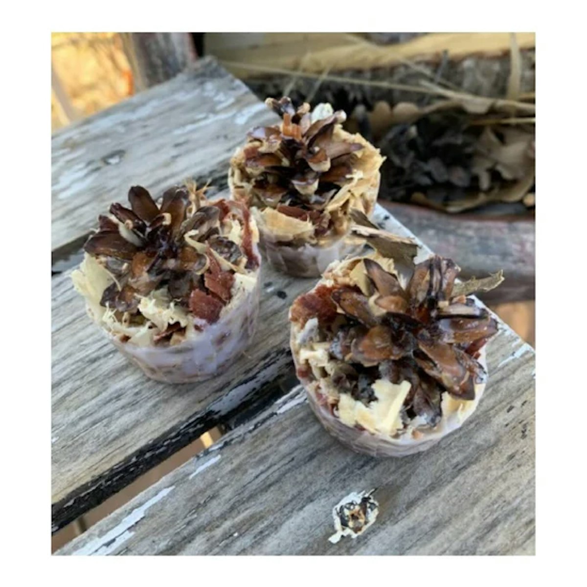 Three pine cones on top of a wooden table.