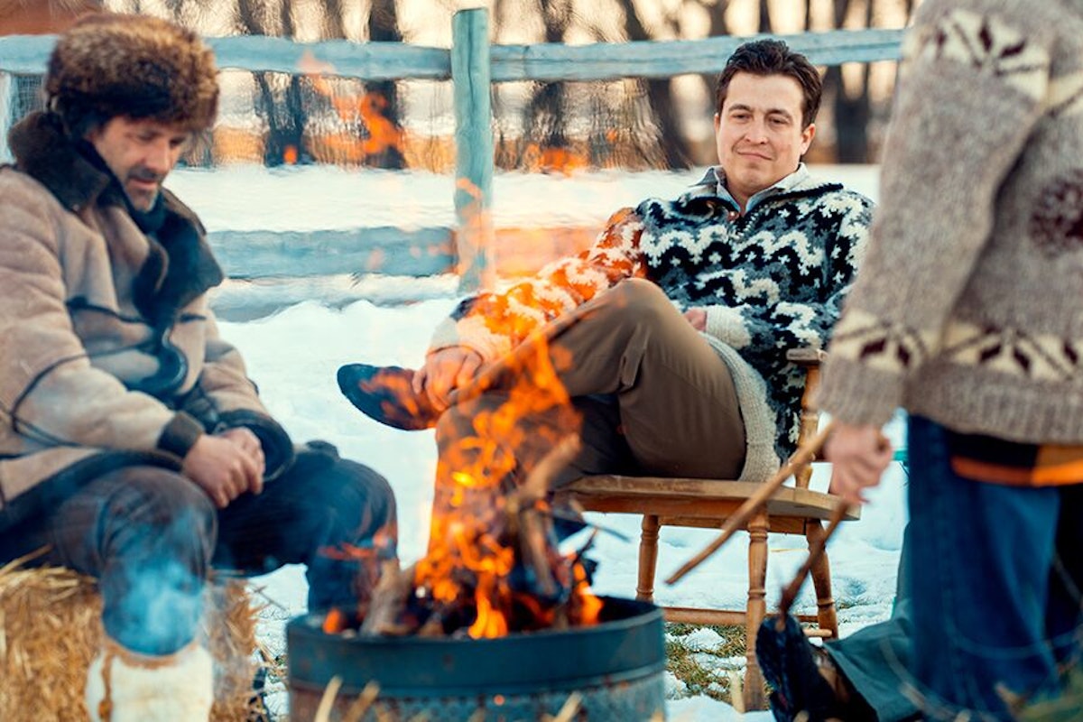 A group of men sitting around a campfire.