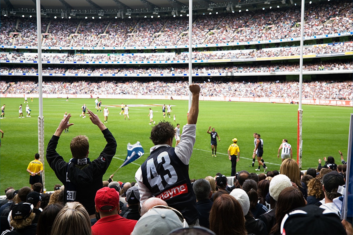 A crowd of people watching an afl game.