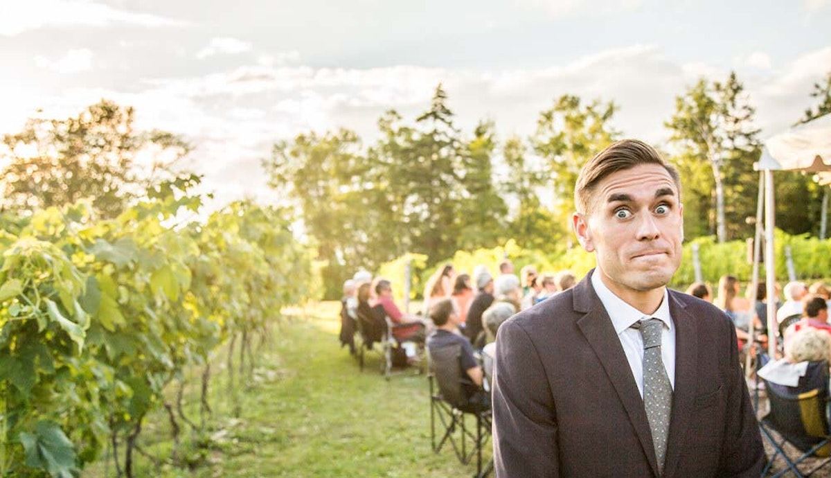 A man in a suit standing in a vineyard.