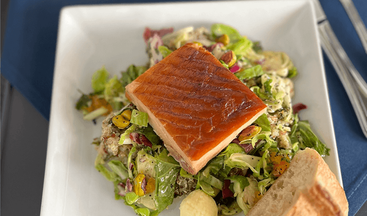 Salmon on a plate with salad and bread.