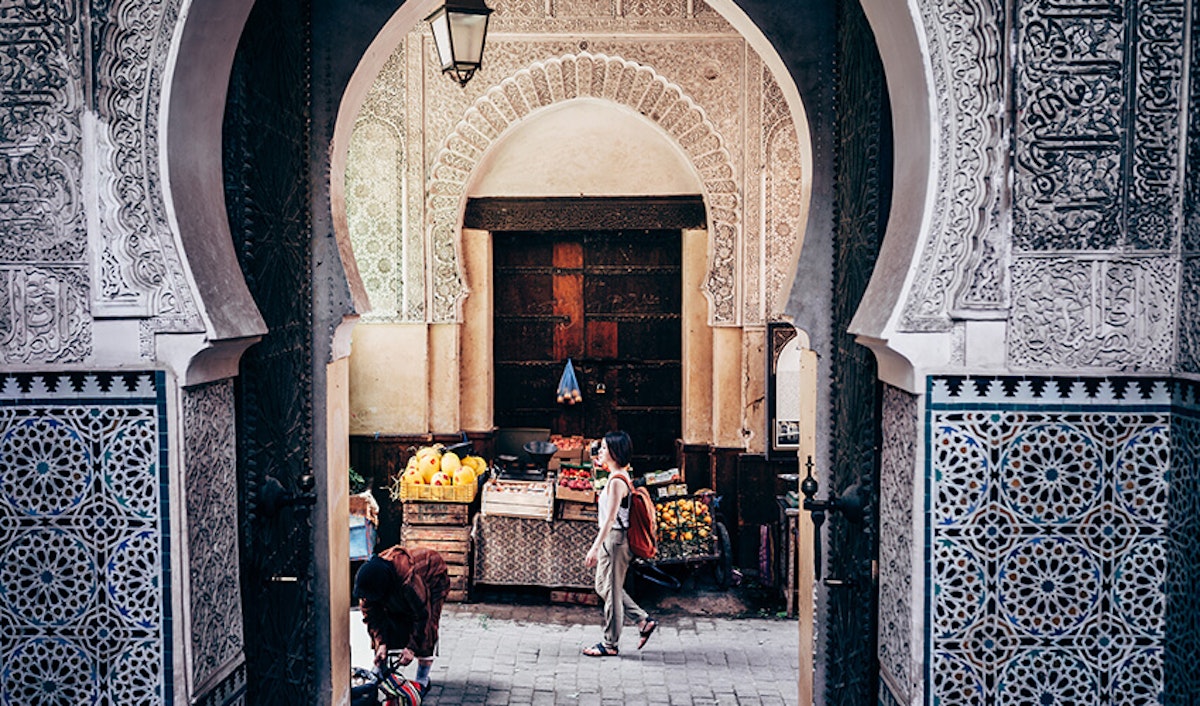 A woman walks through an archway into a market.