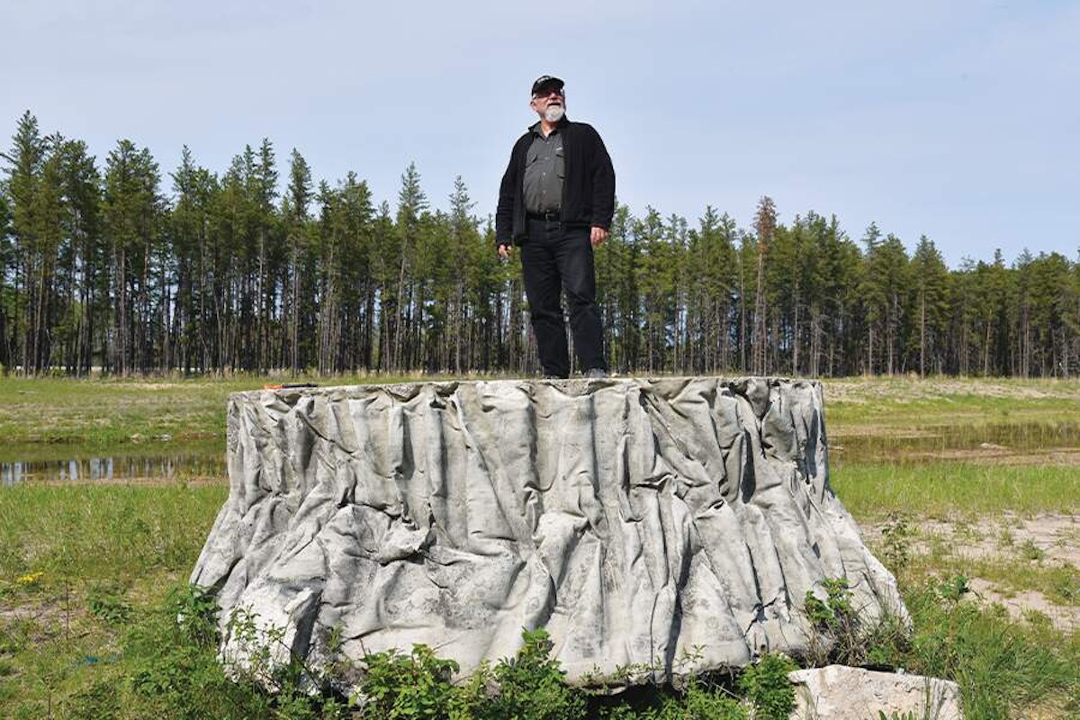 A man standing on top of a tree stump.