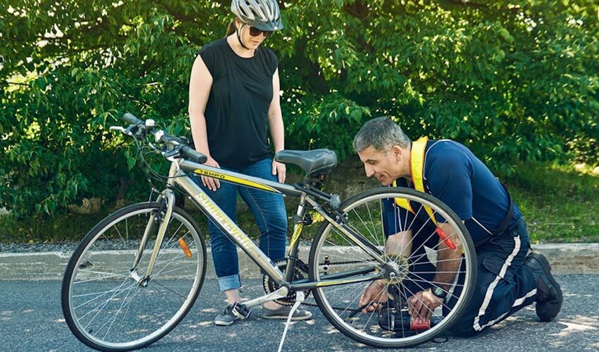 A man and woman fixing a bicycle on the street.