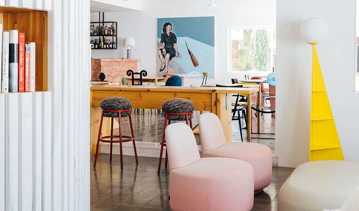 A living room with stools and a painting on the wall.