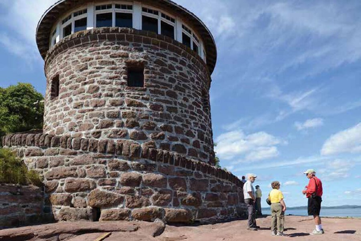 Visitors engaging in a conversation near a round stone tower under a clear sky.