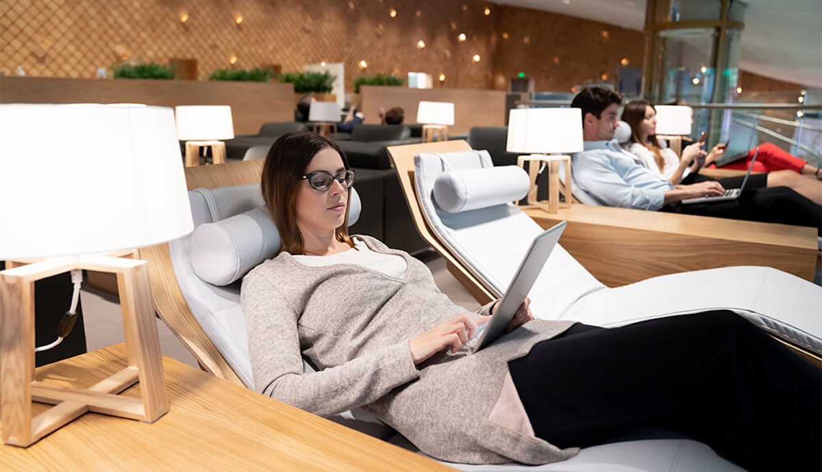 A woman using a tablet in an airport lounge.