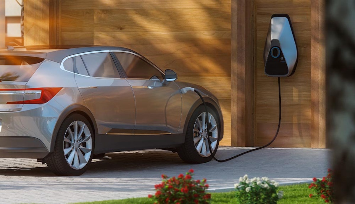 An electric car is parked in front of a garage.