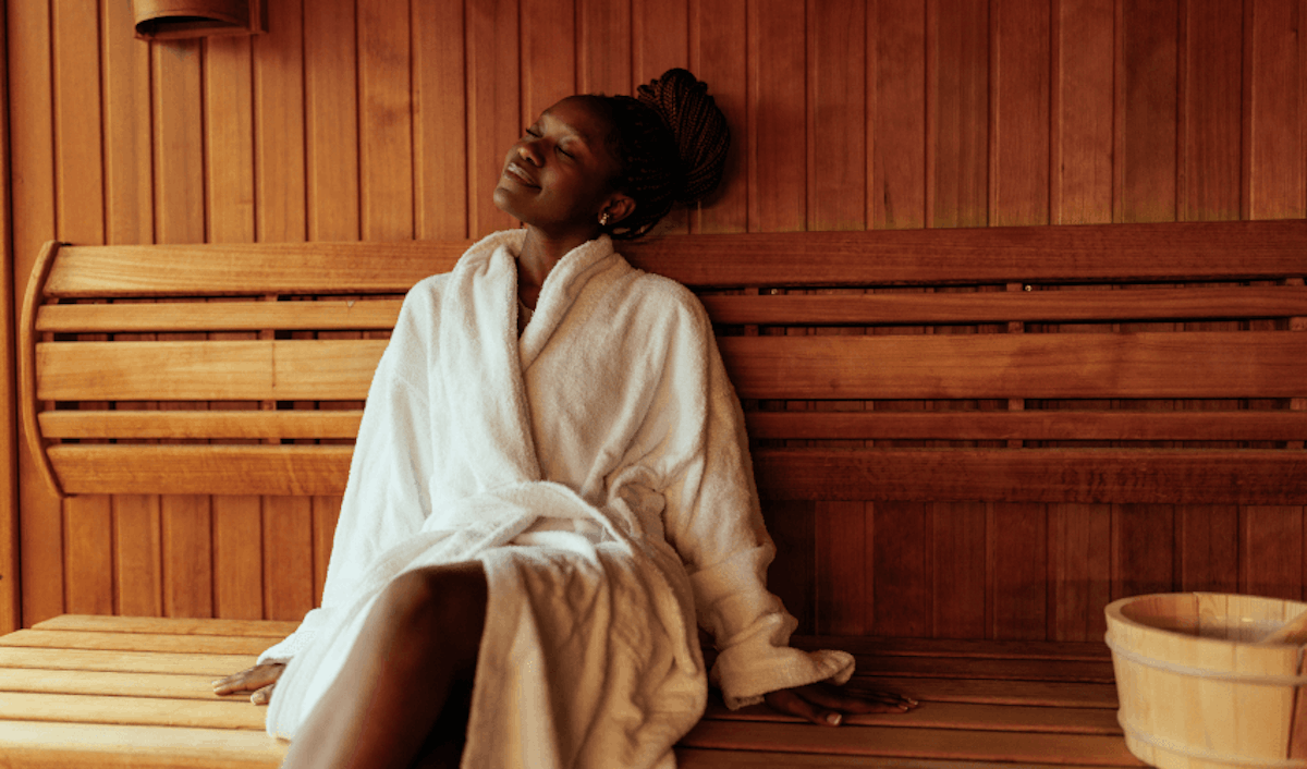 A woman in a white robe sitting in a sauna.