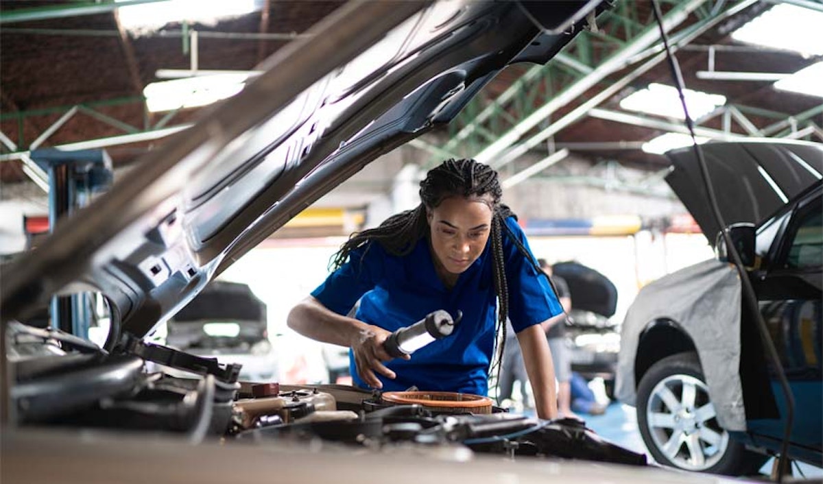 A woman working on a car in a garage.
