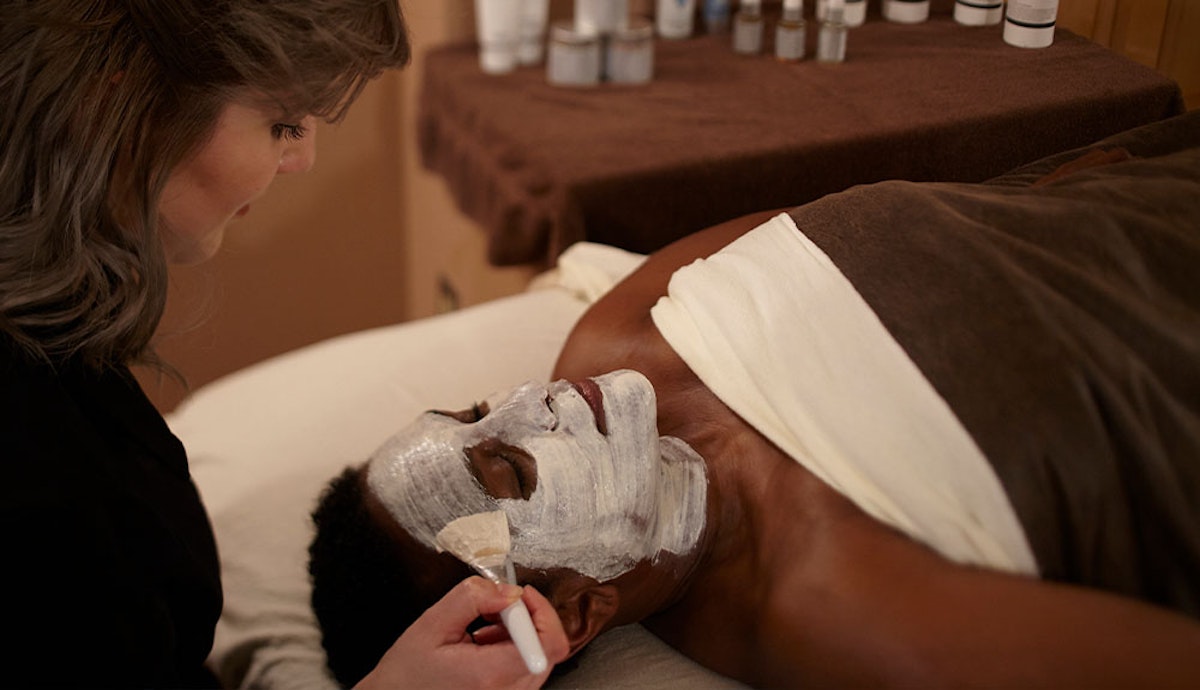 A woman getting a facial mask at a spa.