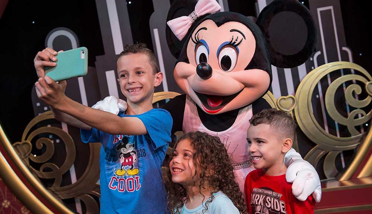 A group of kids taking a selfie with minnie mouse.