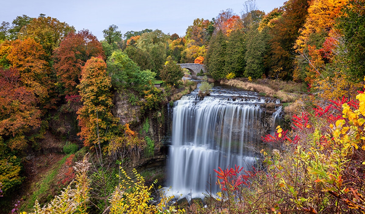 A waterfall surrounded by fall colored trees.