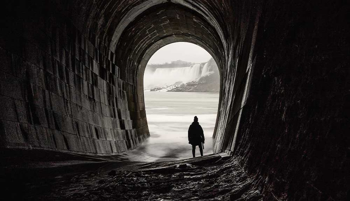 A man is standing in a tunnel near the niagara falls.