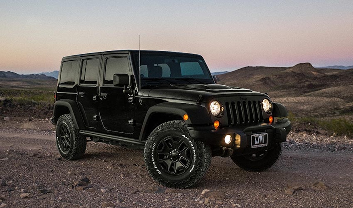 A black jeep parked on a dirt road.