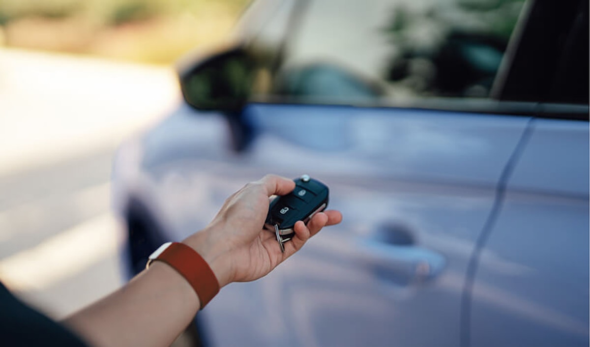 A person holding a key to a blue car.