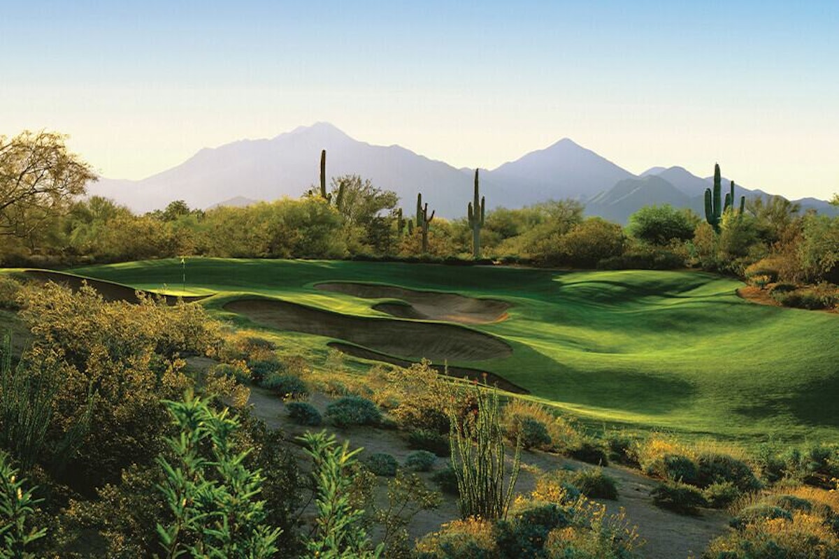 A serene golf course with lush greenery and a mountain backdrop at dusk.