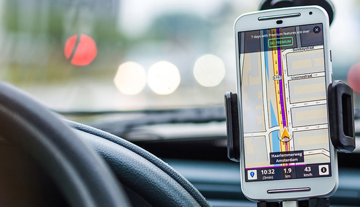 A cell phone displaying a gps on the dashboard of a car.