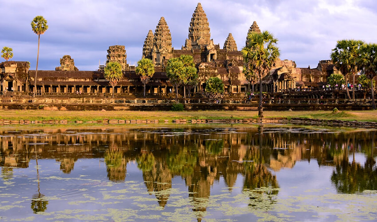 Angkor wat temple complex reflected in water at sunset, cambodia.