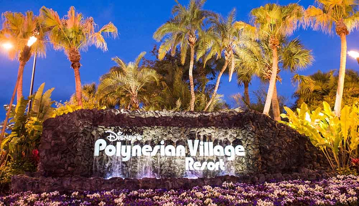 A sign for disney's pigeon village resort at night.