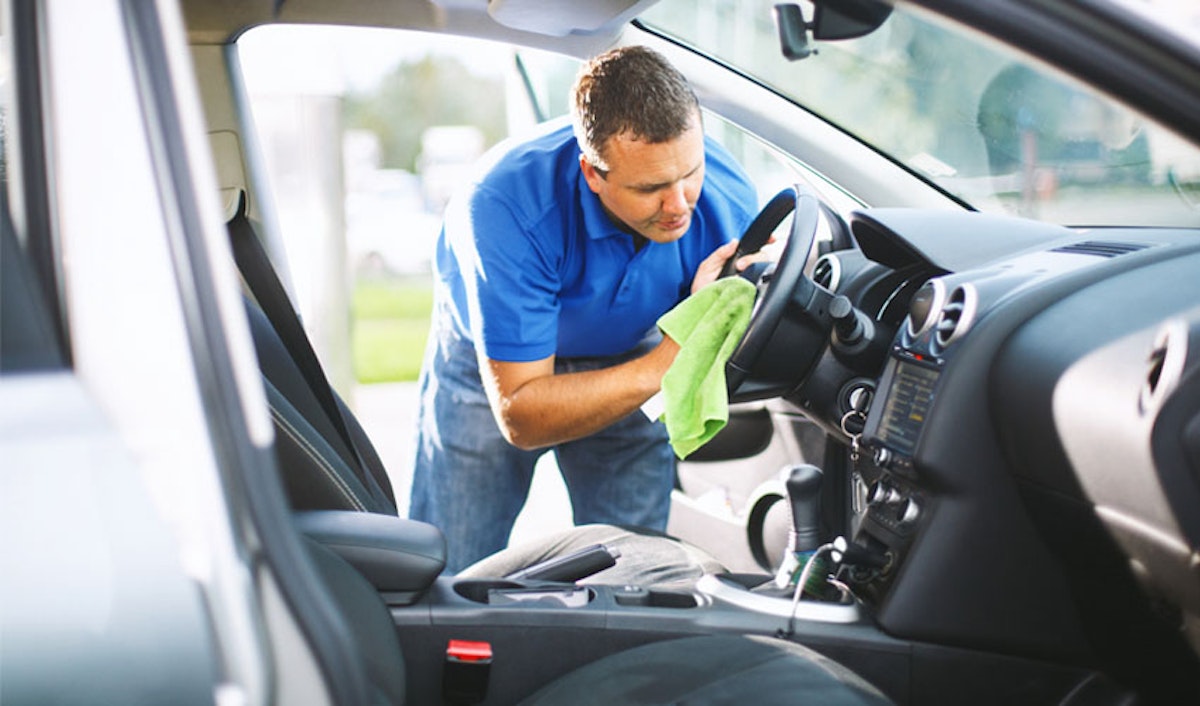 A man cleaning the steering wheel of a car.