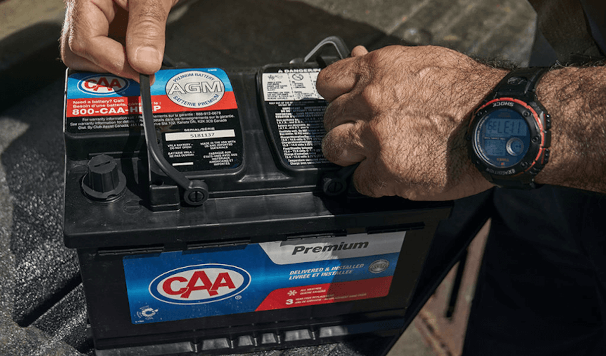 A man is putting a watch on a car battery.