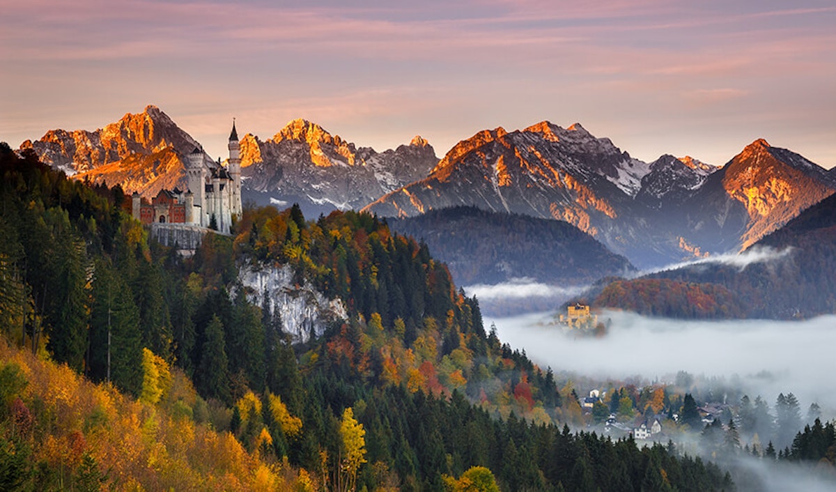 A castle in the mountains with trees in the background.