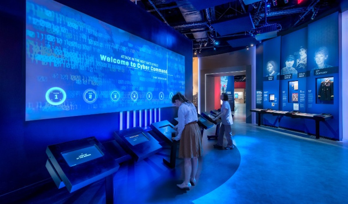 Visitors interact with digital exhibits at a cyber command-themed exhibition.