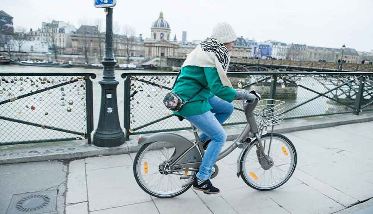 A woman riding a bike on a bridge in paris.