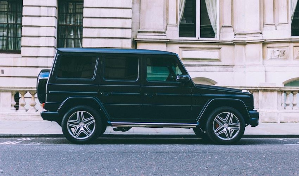 A black mercedes g class parked in front of a building.