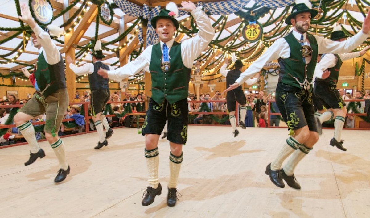 A group of men dressed in traditional bavarian costumes dancing.