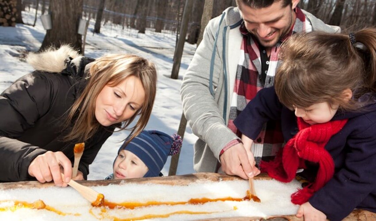 A family is making a snowman in the snow.