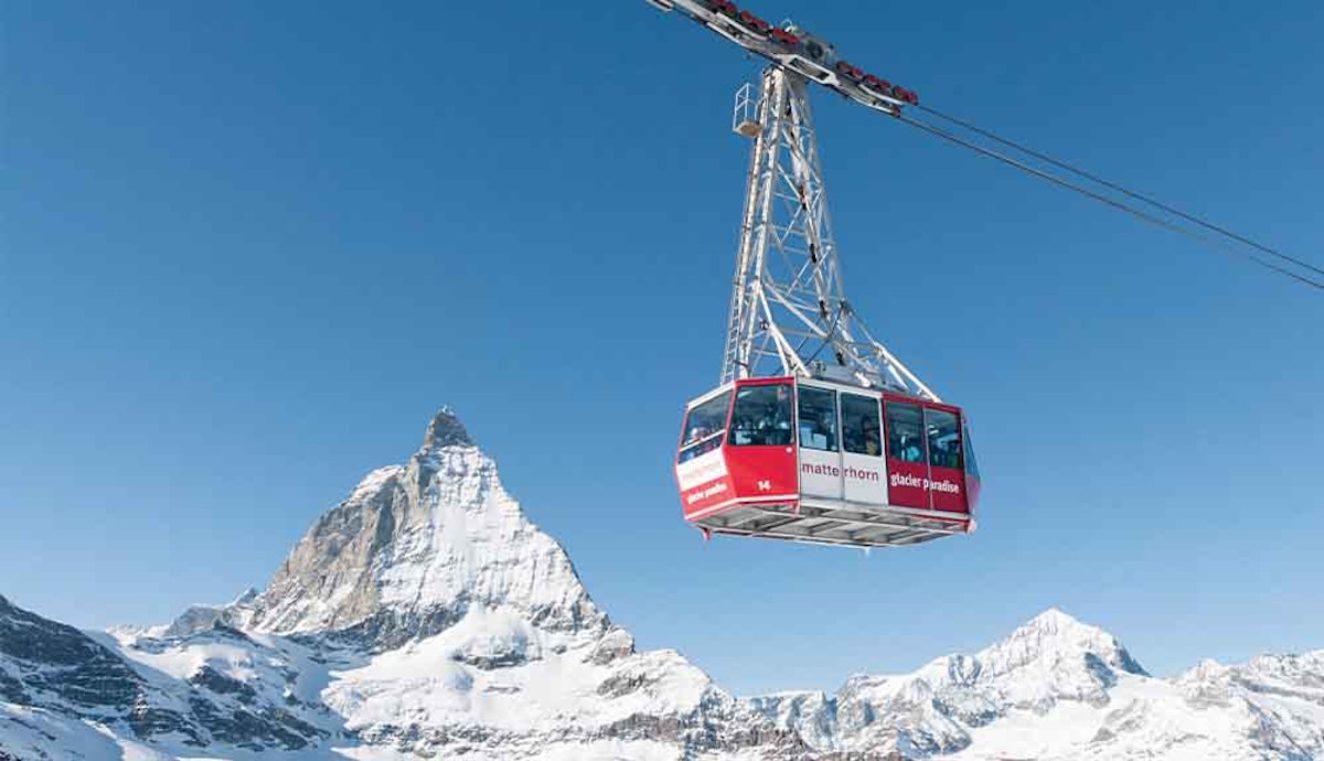 A cable car is flying over a snowy mountain.