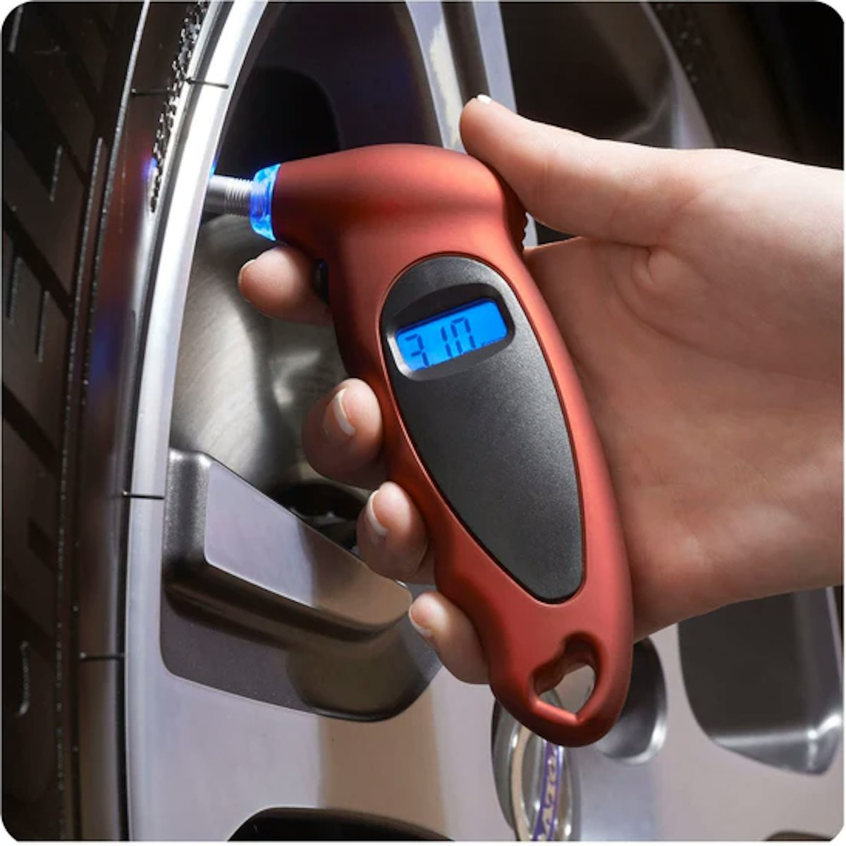 A person using a tire pressure gauge on a tire.