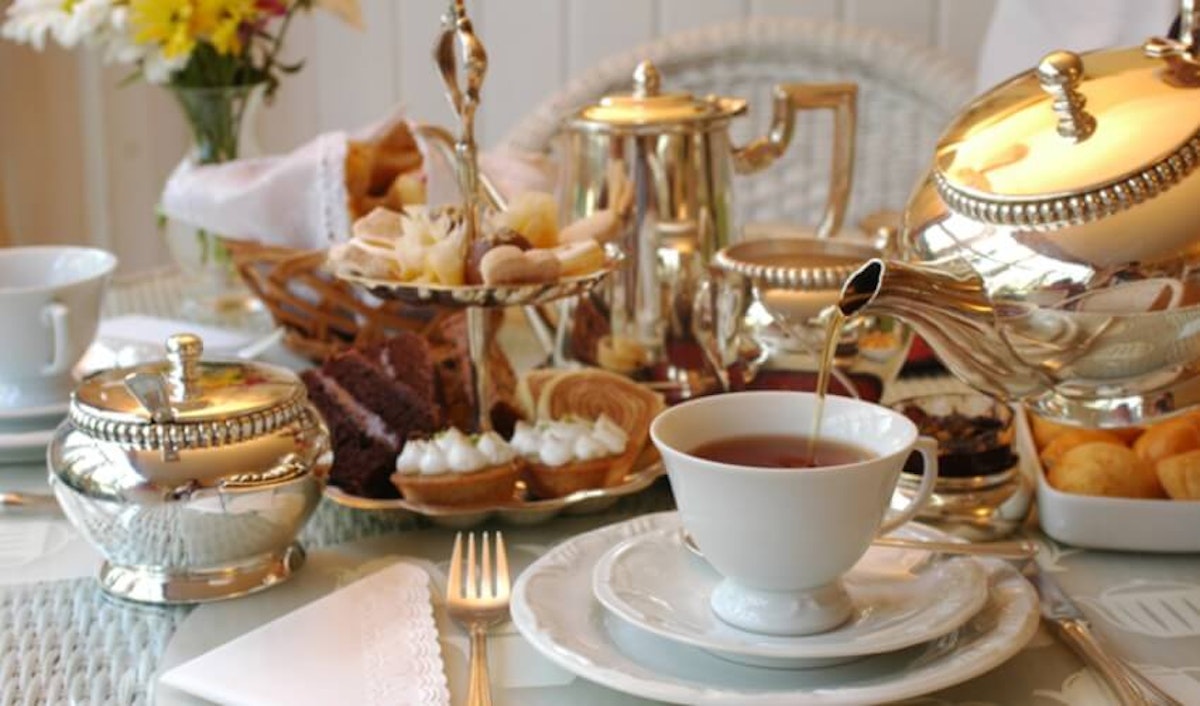 A table is set with a teapot, cups and saucers.