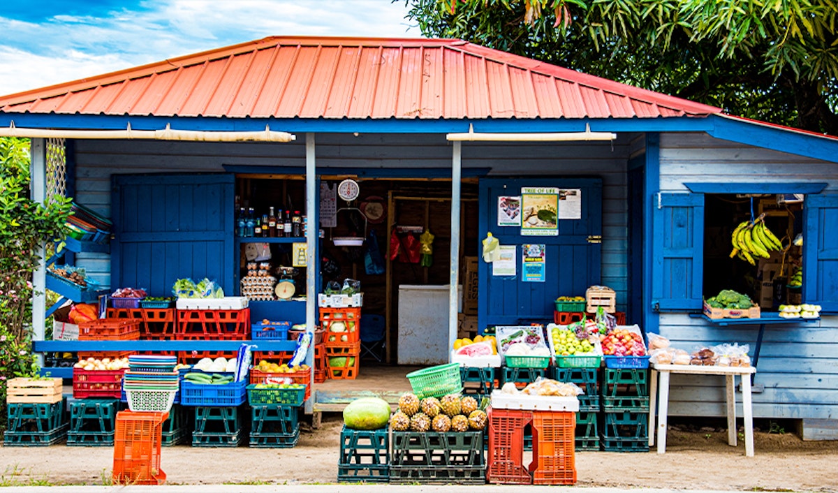 A blue building with crates of fruit and a red roof.