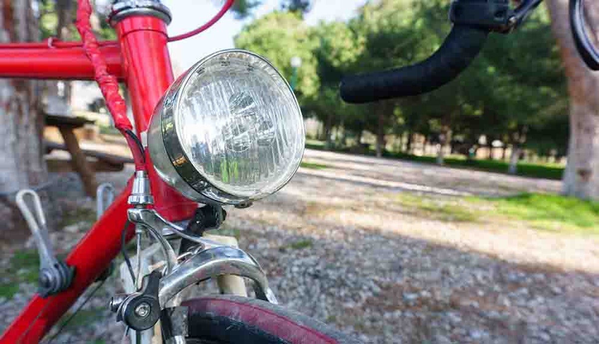 A close up of the headlight of a red bicycle.