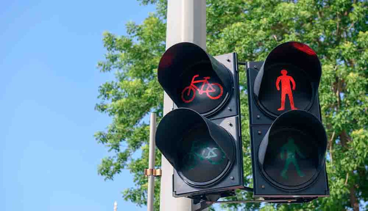 A traffic light with a bicycle and a man on it.