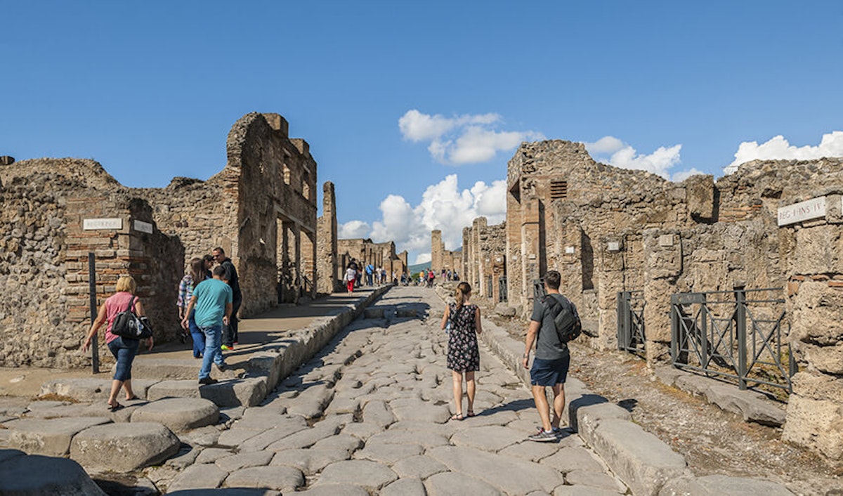 People walking down a cobblestone street in pompeii, italy.
