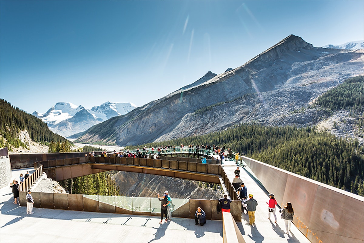 A group of people standing on a walkway in the mountains.