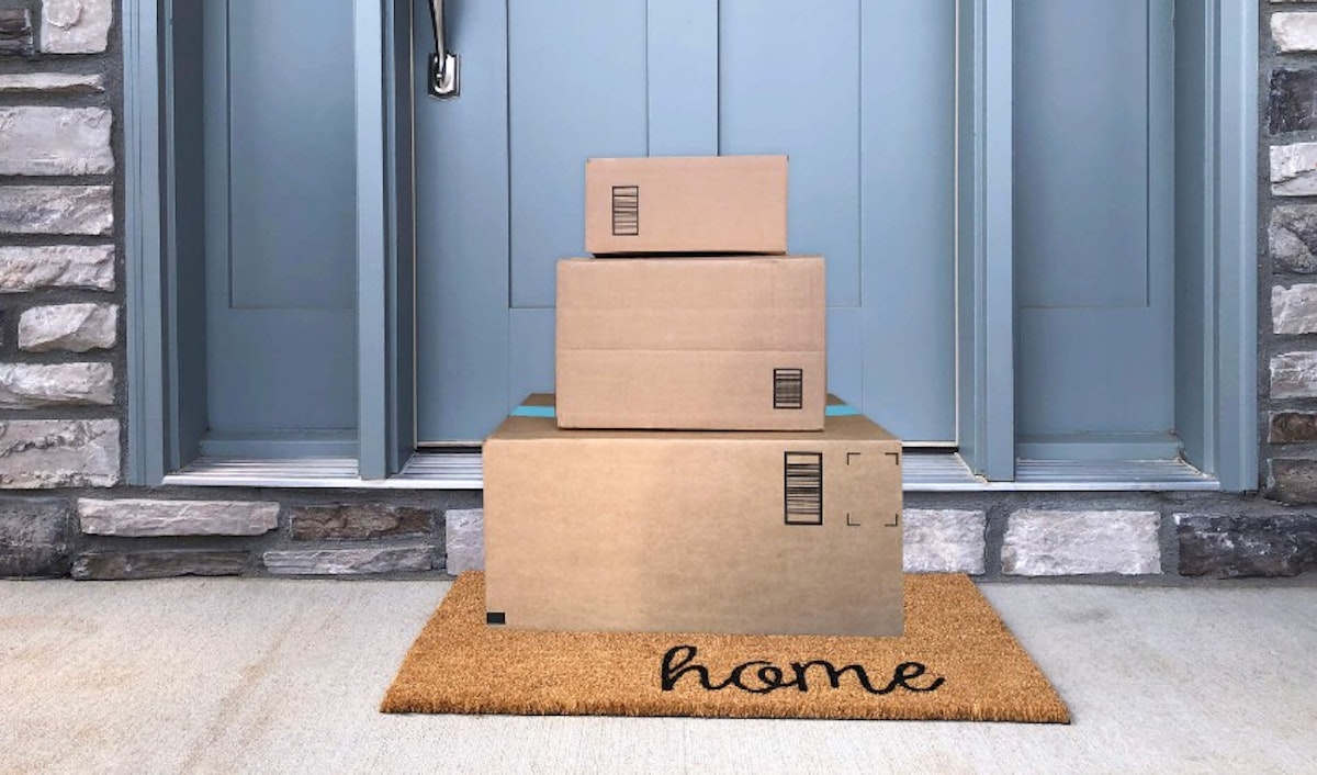 A stack of boxes on a mat in front of a door.