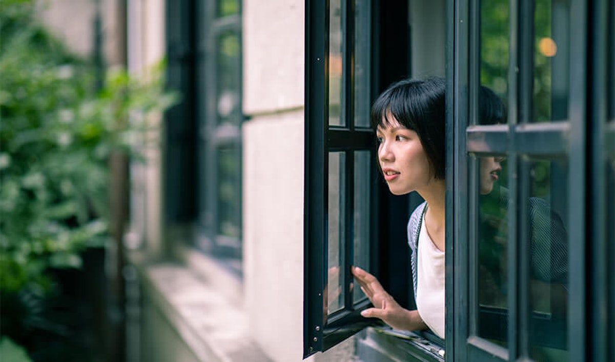 A young asian woman looking out of a window.