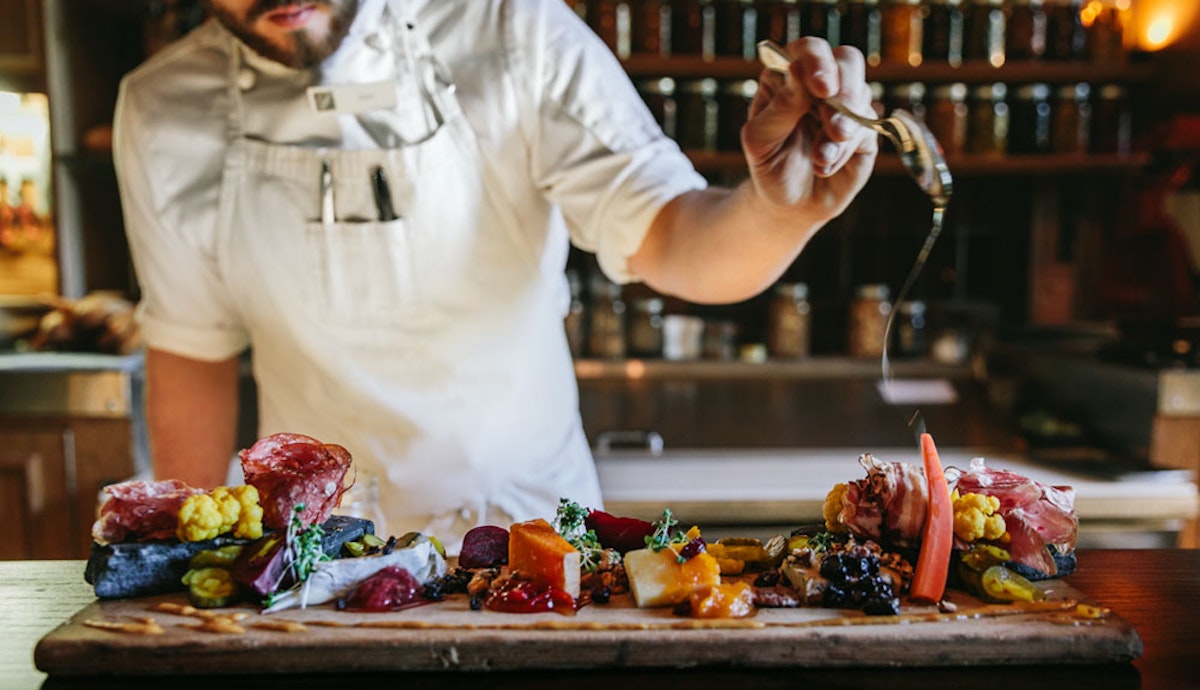 A chef is preparing food on a wooden cutting board.