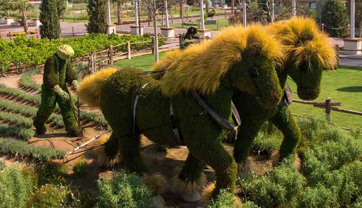 A topiary garden with two horses in the middle.