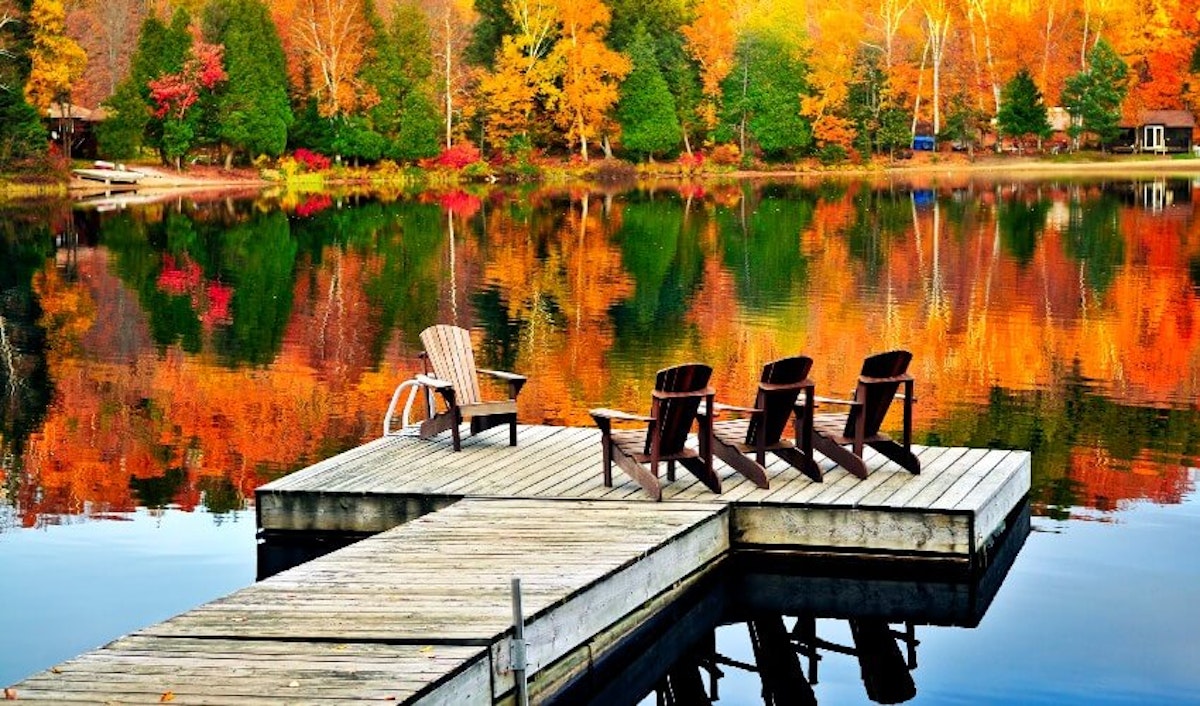A dock with two chairs and a lake in the background.